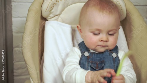 baby sits in chair and plays with a spoon, zoom in