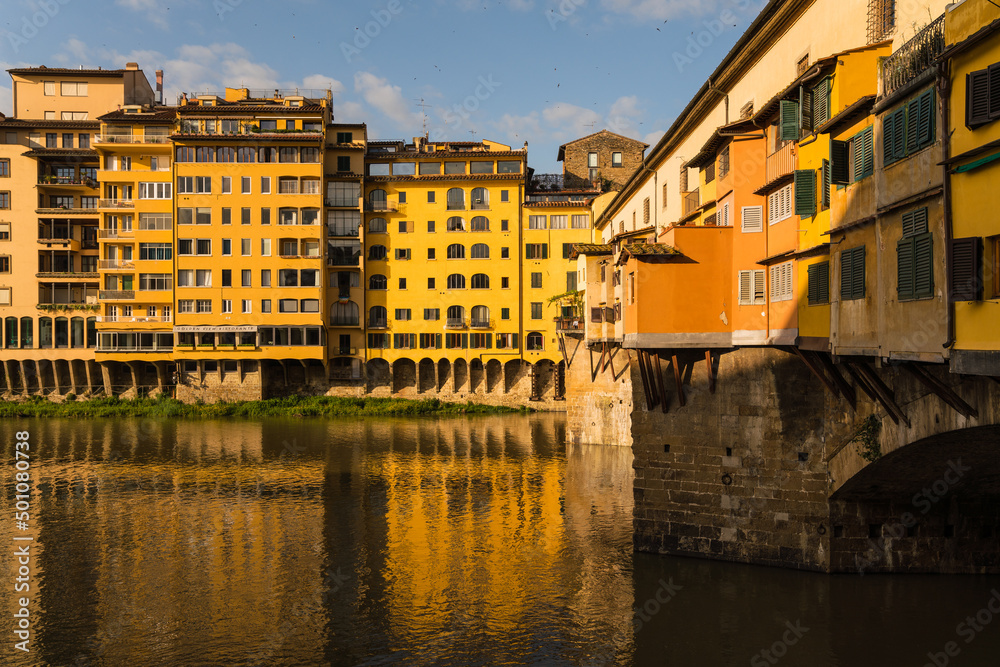 view of Ponte Vecchio and buildings with reflection on the Arno river 