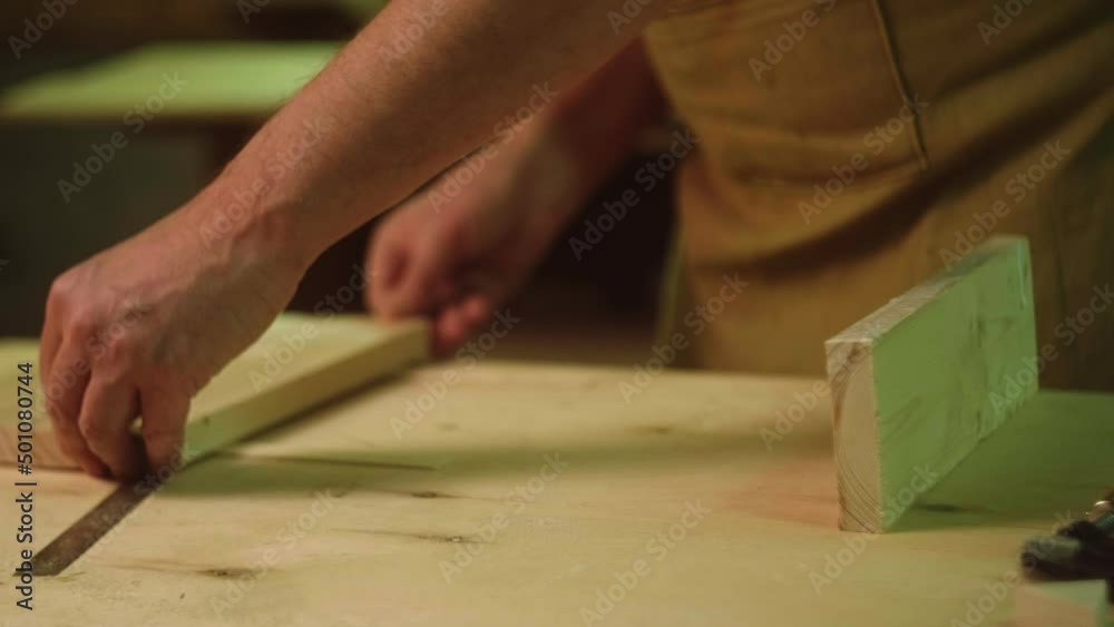 A mature carpenter makes works in his carpentry workshop, glues together wooden blanks A mature carpenter makes works in his carpentry workshop, glues together wooden blanks