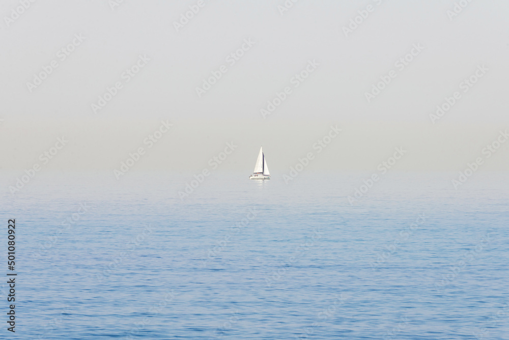 Seascape. Haze over the blue surface of the sea. Yacht on a background of calm sea and blurred horizon.