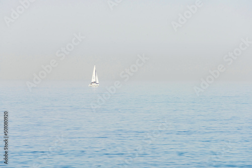 Seascape. Haze over the blue surface of the sea. Yacht on a background of calm sea and blurred horizon.
