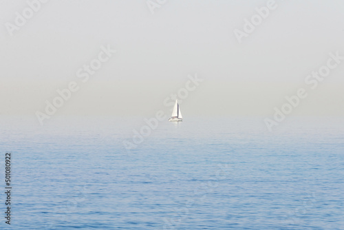 Seascape. Haze over the blue surface of the sea. Yacht on a background of calm sea and blurred horizon.