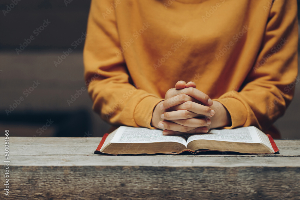 Christian life crisis prayer to god. praying hands, young woman prayer with hands together over a Holy Bible, spiritual light, mind, and soul peace.