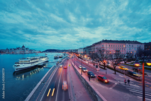 Danube River at blue hour twilight in city of Budapest  Hungary  Cruise and dinner boat near riverside promenade.