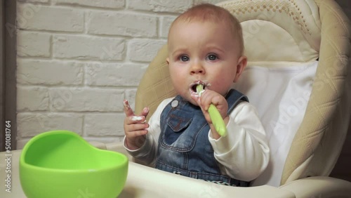 baby sits and eats yogurt with spoon, tracking shot