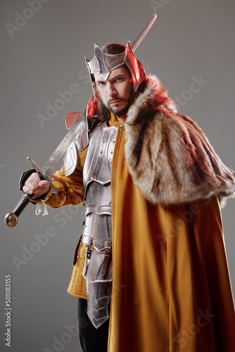 Fototapeta The King. Handsome Medieval knight in armor holding sword.