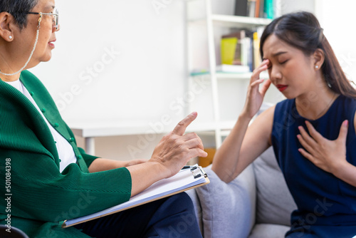 Asian psychologist doctor having session with young depressed woman in clinic. Psychology and mental therapy concept.