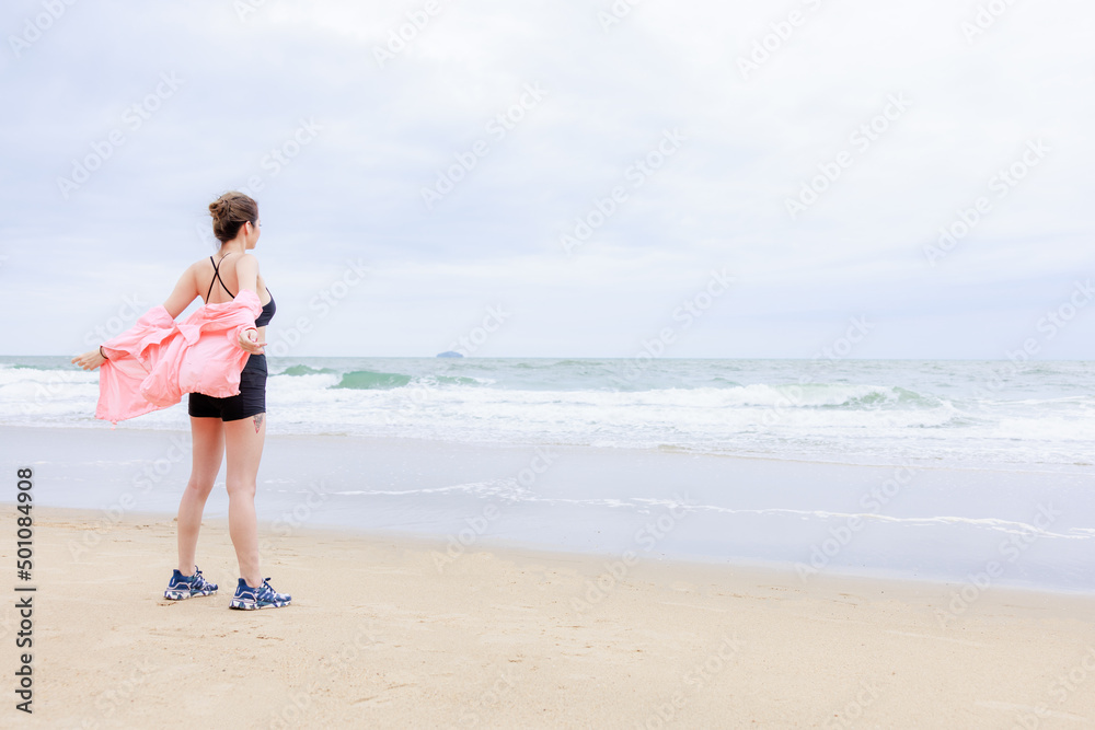 asian woman wearing sportwear and pink jacket exercise and relax on the sea beach at evening in the rain season asian woman wearing sportwear and pink jacket exercise and relax on the sea beach at evening in the rain season