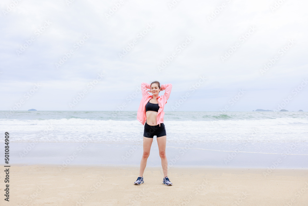 asian woman wearing sportwear and pink jacket exercise and relax on the sea beach at evening in the rain season asian woman wearing sportwear and pink jacket exercise and relax on the sea beach at evening in the rain season