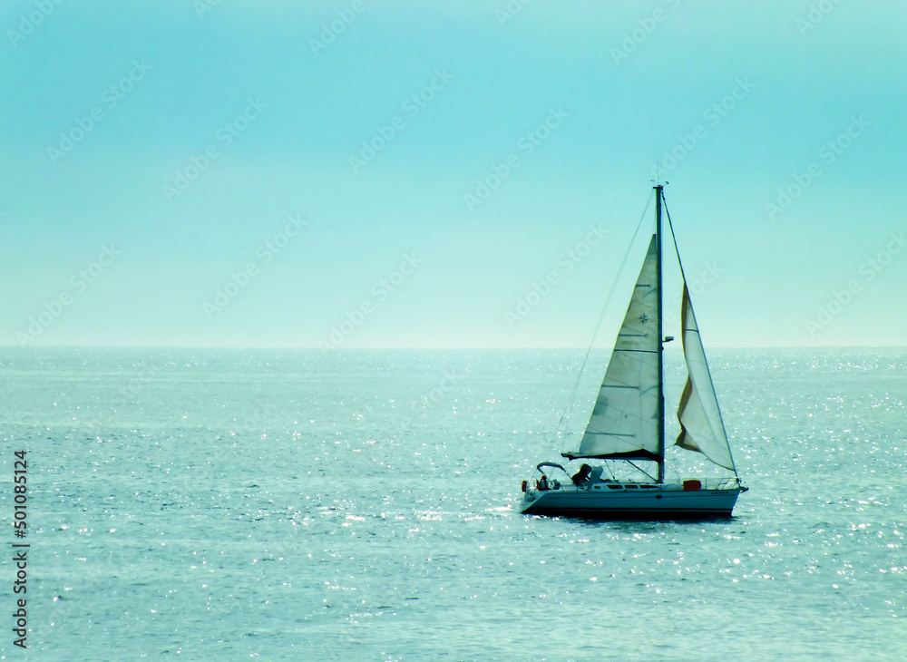 A sailing boat in a beautiful blue sea, a photo of a sailboat in turquoise ocean, sun rays hitting the sea in the afternoon, Barcelona, Spain, Marina in Barcelona, selective focus