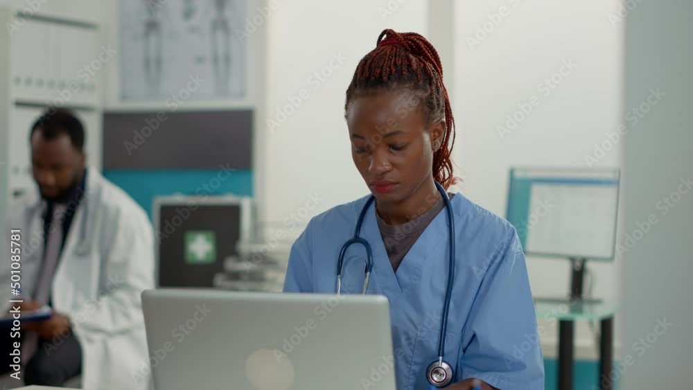 Portrait of health care service worker using laptop in cabinet, helping doctor with patient appointment. Medical assistant working on computer to plan checkup visit at office desk.