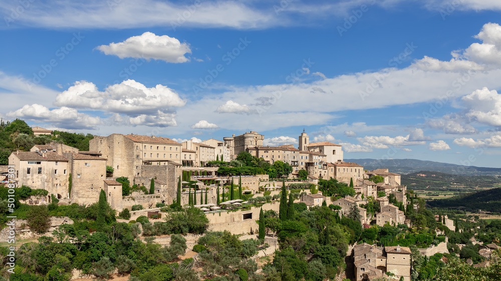 Breathtakingly picturesque sky with floating white clouds over medieval Gordes village, rock and Luberon valley. Vaucluse, Provence, France
