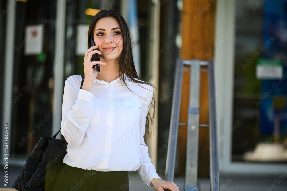 Fototapeta premium Portrait of a young woman talking on the phone on stairs outdoor