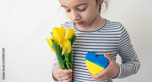 Little girl with a bouquet of tulips and a heart with the flag of Ukraine.