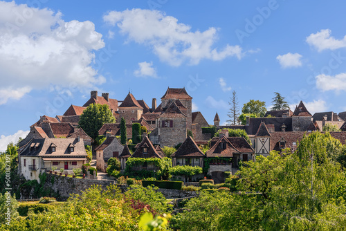 Panoramic view of toy small medieval Loubressac village with stone houses with sloping roofs surrounded by lush vegetation. Lot, Occitania, France