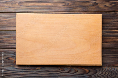 Top view of wooden cutting board on wooden background. Empty space for your design.=