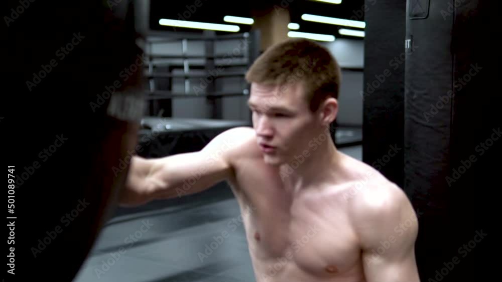 The gym in in grsh bandages black man beats A boxer bag man, concept healthy lifestyle hitting glove from sport from professional power, strong kick. Adult challenge dark, slow motion