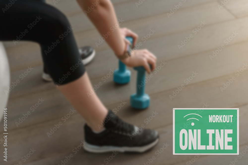 sign online workout, due to the closure of the hall during the lockdown. close up Young athletic woman training with exercise ball and dumbbells sign online workout, due to the closure of the hall during the lockdown. close up Young athletic woman training with exercise ball and dumbbells