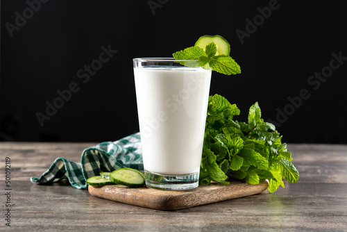 Ayran drink with mint and cucumber in glass on wooden table. Copy space photo