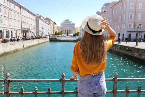 Tourism in Italy. Back view of pretty girl holding hat in Trieste, Italy. Beautiful young woman visiting Europe. photo