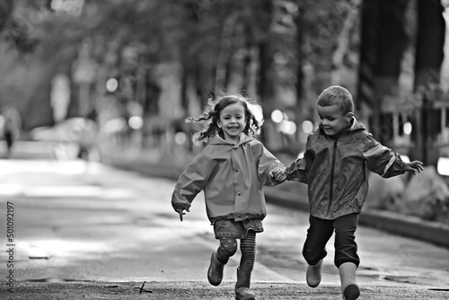 boy and girl children on an autumn walk in the park / autumn park, raincoats for children, family