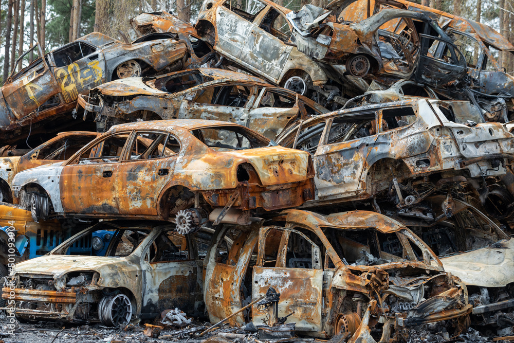 Many shot and destroyed cars of civilians at the car graveyard in Irpin, Ukraine. War in Ukraine. Car accident.