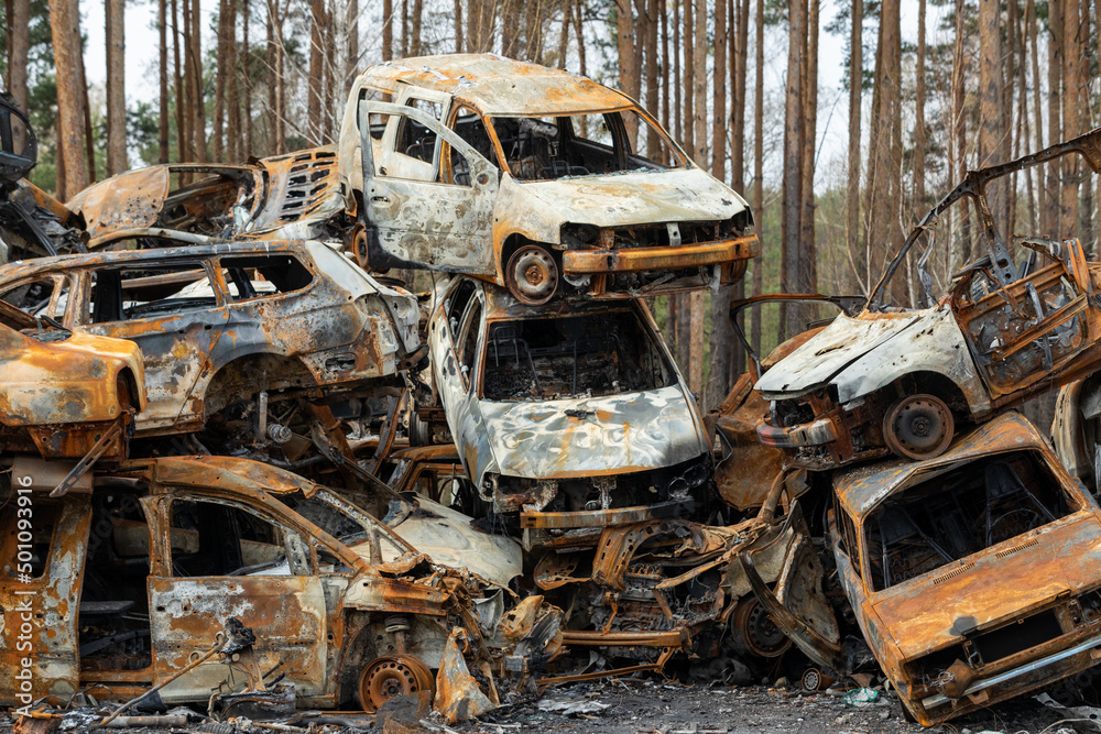 Fototapeta premium Many shot and destroyed cars of civilians at the car graveyard in Irpin, Ukraine. War in Ukraine. Car accident.