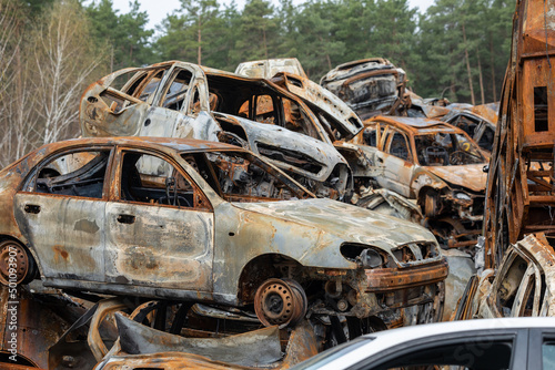 Many shot and destroyed cars of civilians at the car graveyard in Irpin, Ukraine. War in Ukraine. Car accident.