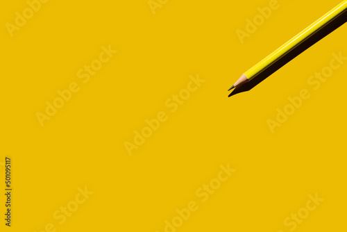 top view of sharp pencil on yellow background.