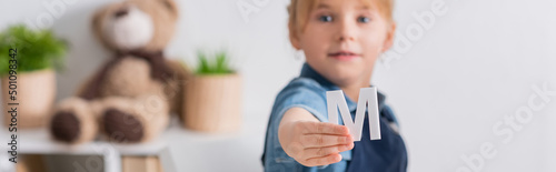 Schilderij op canvas Blurred kid holding letter in classroom, banner.
