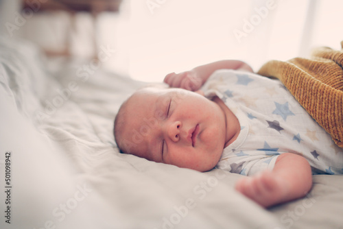 Cute sleeping chubby baby in a bed on a linen bedspread, a baby with chubby cheeks sleeps on a big bed