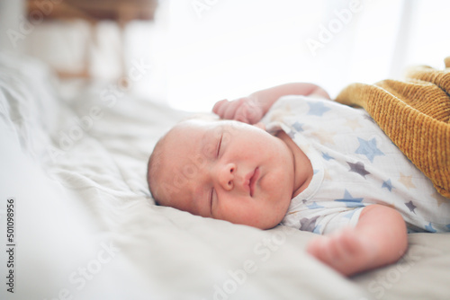 Cute sleeping chubby baby in a bed on a linen bedspread, a baby with chubby cheeks sleeps on a big bed