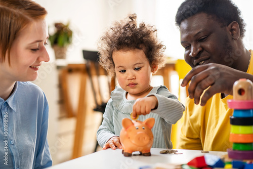 Photos Kid inserting a coin into a piggy bank, financial concept