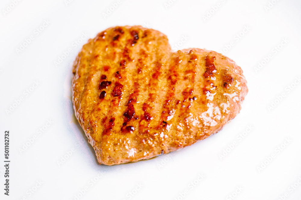 Meat cutlet in the shape of a heart. Dinner for lovers on February 14. Meat love. Valentine's Day. Eating minced heart on a plate Meat cutlet in the shape of a heart. Dinner for lovers on February 14. Meat love. Valentine's Day. Eating minced heart on a plate
