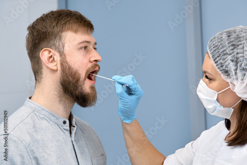 the doctor takes a smear for a PCR test from a young man