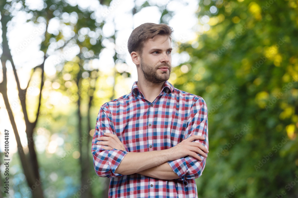 young man in checkered shirt with crossed hands outdoor