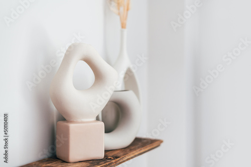 Fotografering Modern beige ceramic vases with dry flowers on wooden shelf with white wall