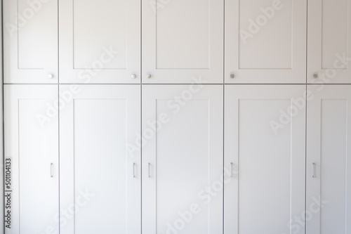 Modern new fitted tall cupboards in kitchen light grey color, interior trendy units. Huge storage inside house, built in wardrobe