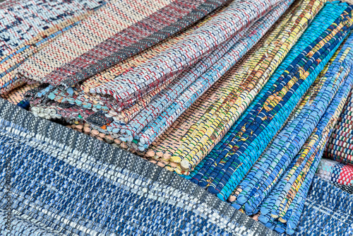Homemade colourful woven rugs made of fabric ribbons stacked. Close-up.