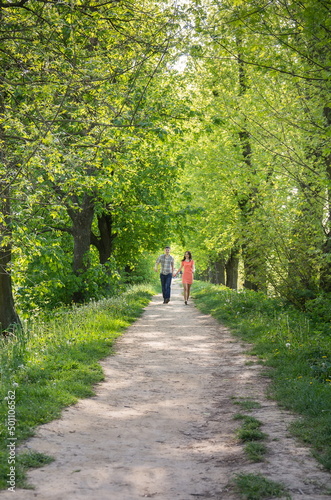 A young couple in love, a guy and a girl, run along the park alley towards them.
