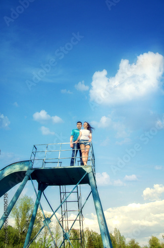 A man and a woman - a couple in love on a metal structure against a blue sky