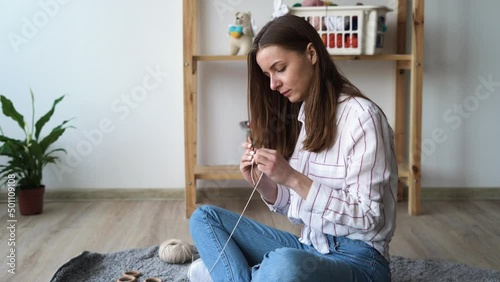 hobby and needlework concept, knitting young woman knits crochet scarf with woolen threads sitting on the floor, leisure photo