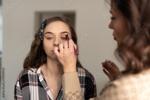 Make-up artist applies makeup to the girl's eyebrows with a brush