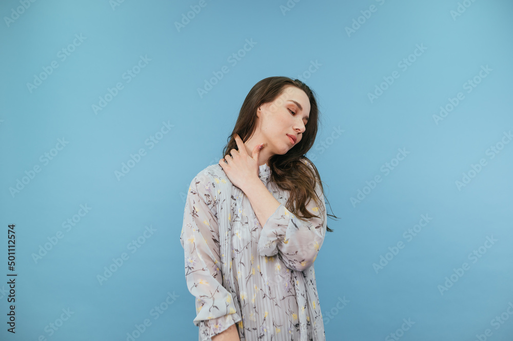 Cute gentle woman in dress isolated on blue background, looking aside Cute gentle woman in dress isolated on blue background, looking aside