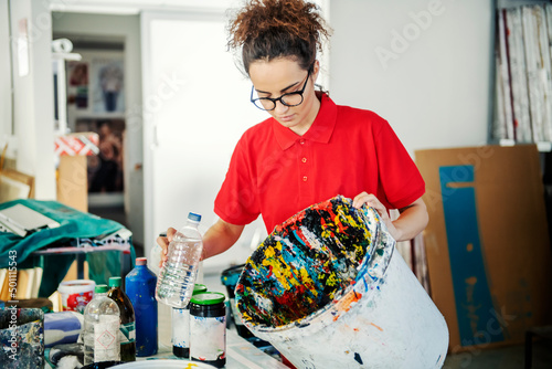 A printing shop employee cleaning bucket for mixing colors with paint thinner.