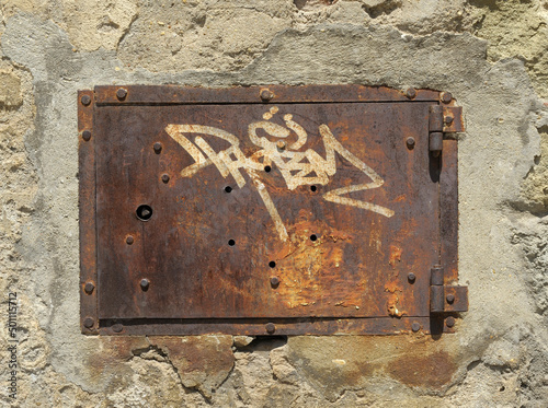 Rostige Klappe in einer verwitterten Mauer