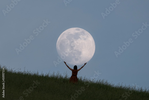Full moon portrait at blue hour with a girl holding the moon above her head, Emilia Romagna photo