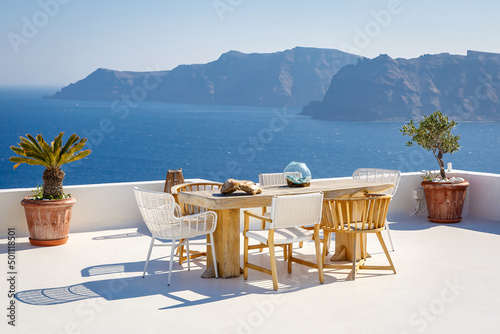 A sun terrace for rest with a wooden table and chairs in Thira, Santorini island, Greece
