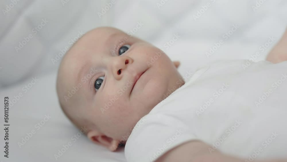 Cute newborn boy lying in bed with soft white linen Cute newborn boy lying in bed with soft white linen