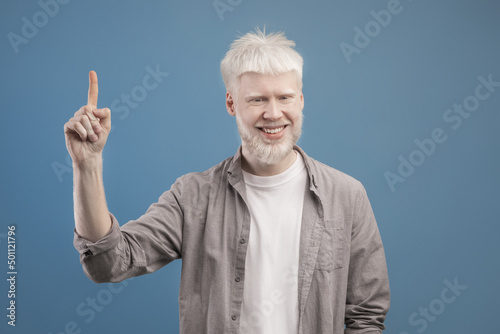 Handsome young albino guy pointing upwards experiencing AHA moment, having creative idea, gesturing eureka